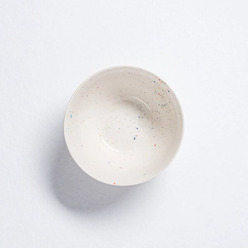 Peut inclure: Un bol en c&eacute;ramique blanche avec un motif mouchet&eacute; de points bleus, rouges et jaunes.
