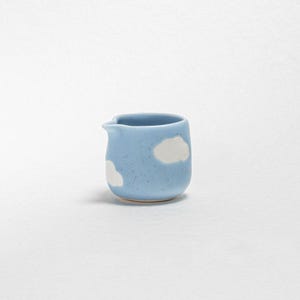 Könnte beinhalten: Ein kleiner, hellblauer Keramik-Milchkännchen mit einem weißen Wolkenmuster.