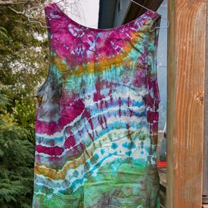 Peut inclure: Une robe sans manches en tie-dye avec deux poches. La robe est un m&eacute;lange de couleurs bleues, vertes, roses et jaunes.