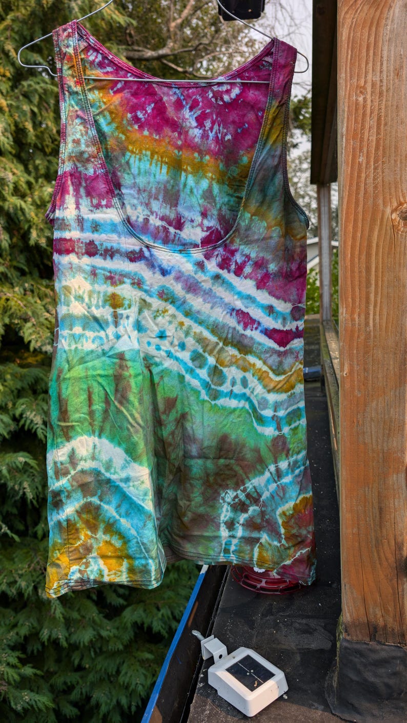 Peut inclure: Un d&eacute;bardeur tie-dye avec un motif en spirale color&eacute; dans des tons de rose, bleu, vert et jaune. Le d&eacute;bardeur est suspendu &agrave; une corde &agrave; linge.