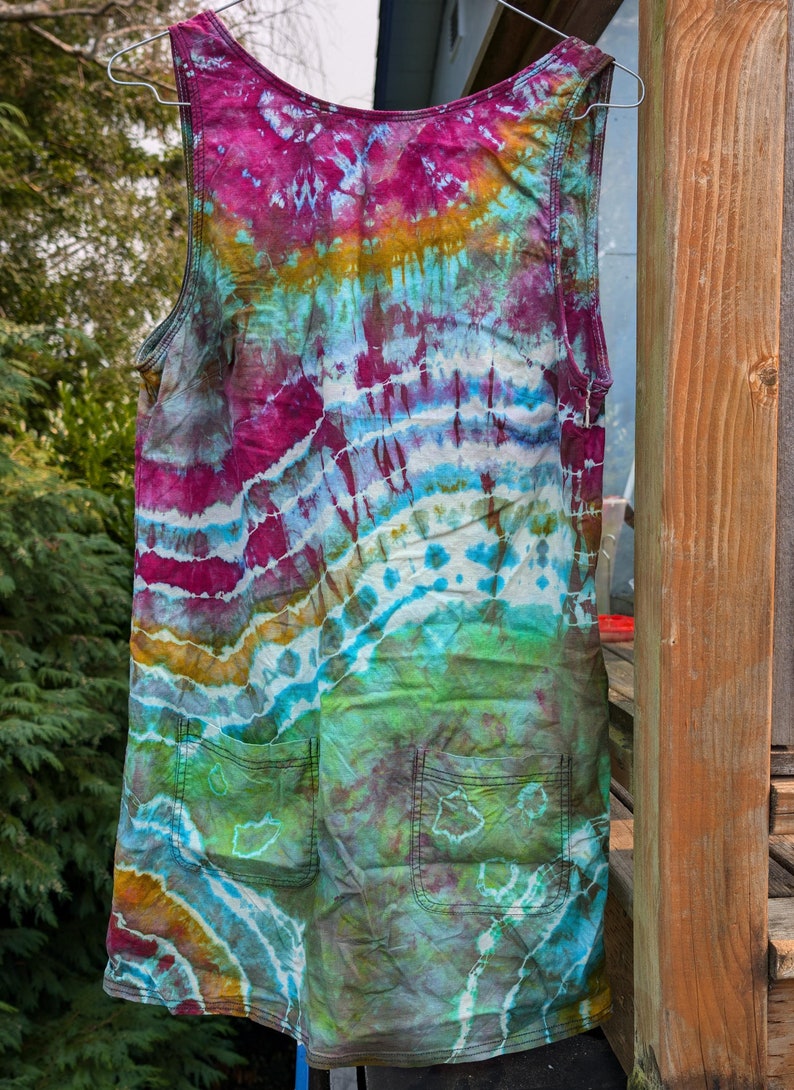 Peut inclure: Une robe sans manches en tie-dye avec deux poches. La robe est un m&eacute;lange de couleurs bleues, vertes, roses et jaunes.