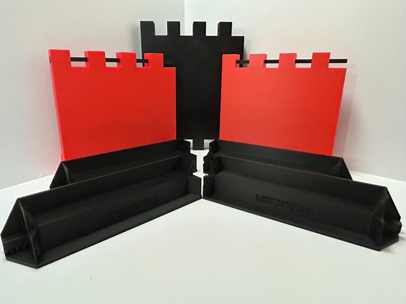 May include: A set of black and red castle-themed building blocks. The set includes red wall pieces with black horizontal bars and black base pieces. The blocks are arranged on a white surface.