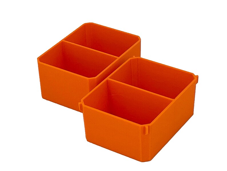 May include: Two orange plastic storage bins, each with two compartments. These bins are designed for storing small items, perfect for organising a workspace or craft area. They are made of durable plastic.