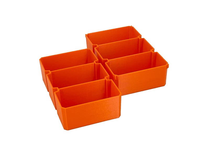 May include: Six bright orange rectangular storage bins. The bins are arranged in a cluster, with three on top and three below. The bins are made of a solid material and have a smooth finish. They are designed for organizing small items.