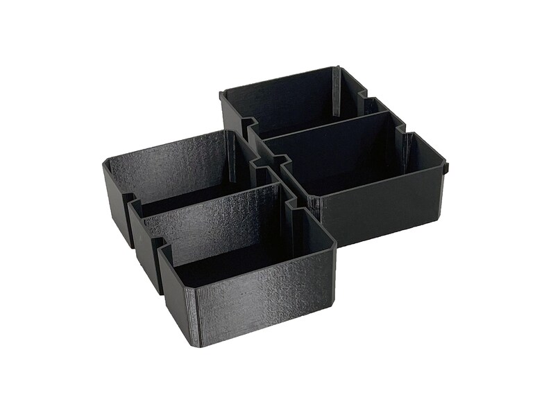May include: A black plastic organizer with four compartments. The organizer is designed to fit together, with two sections of two compartments each. The compartments are rectangular and have a textured surface.