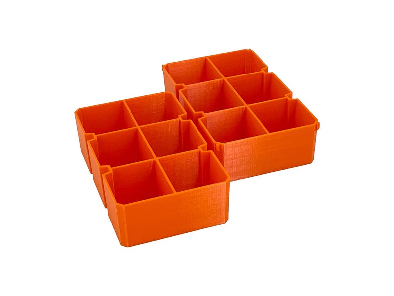 May include: Orange plastic storage organizers with six compartments each. The organizers are arranged in a cluster, ideal for organizing small items. The design is simple and functional, suitable for various storage needs.