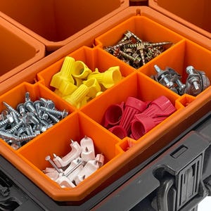 May include: An orange and black toolbox with various hardware components. The toolbox is divided into compartments filled with screws, wire connectors, and other small parts. The image is a close-up shot of the open toolbox.