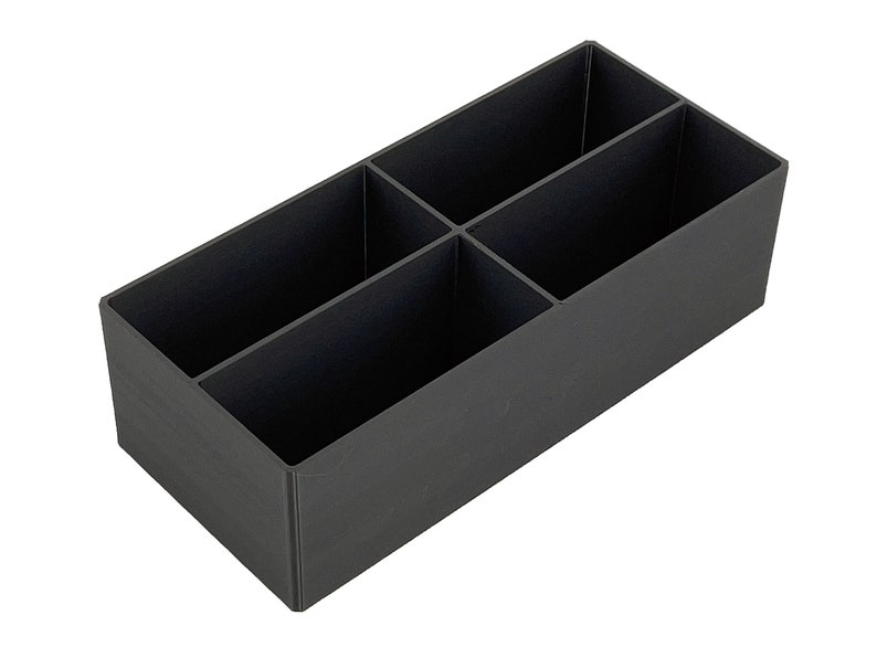 May include: A black plastic organiser with four compartments. The organiser is rectangular and has a smooth surface.