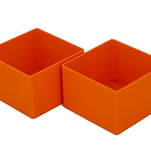 May include: Two orange square-shaped storage boxes. The boxes are made of a sturdy material and have a smooth finish.