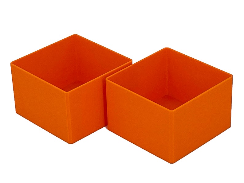 May include: Two orange square-shaped storage boxes. The boxes are made of a sturdy material and have a smooth finish.
