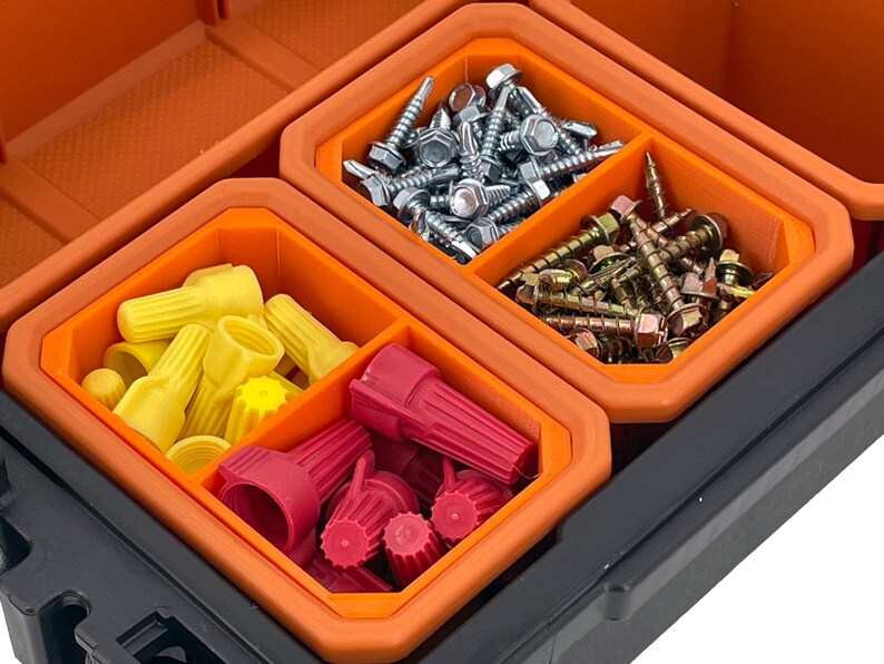 Puede incluir: Una caja de herramientas de pl&aacute;stico naranja y negro con cuatro compartimentos. Los compartimentos est&aacute;n llenos de varios art&iacute;culos de ferreter&iacute;a, incluidos conectores de cables, tornillos y clavos.