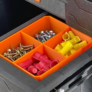 Pode incluir: Uma gaveta aberta com um organizador laranja contendo v&aacute;rios itens de hardware. Os compartimentos cont&ecirc;m parafusos, parafusos, conectores de fio e outras pe&ccedil;as pequenas. A gaveta faz parte de um sistema de armazenamento preto maior.