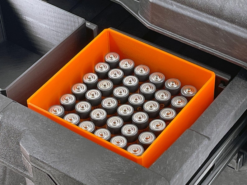 May include: An orange plastic storage container filled with a large quantity of AA batteries.