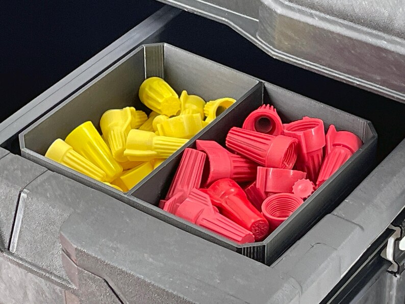May include: A gray storage container with two compartments, one filled with yellow wire connectors and the other with red wire connectors. The connectors are various sizes and shapes.