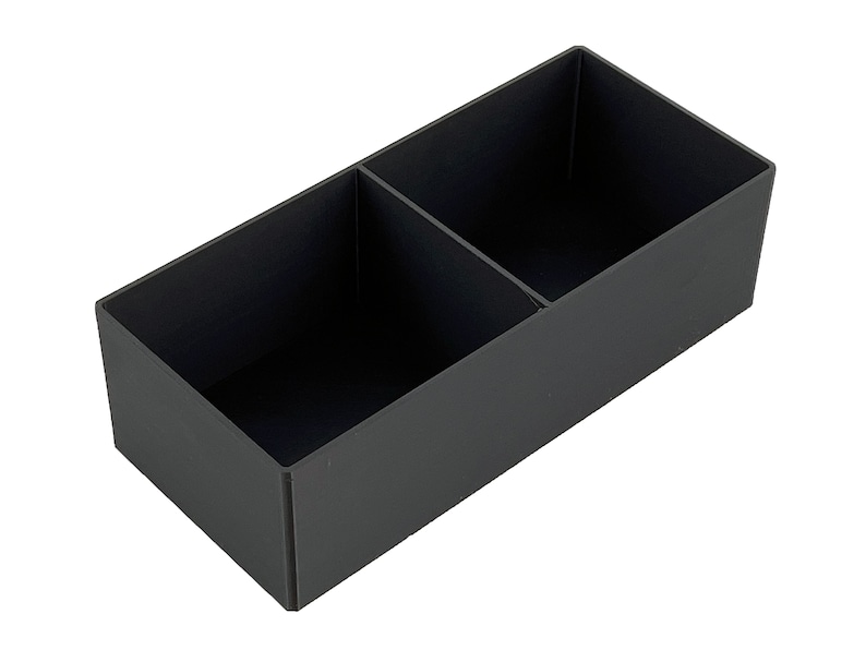 May include: A black rectangular storage box with two compartments. The box is made of a sturdy material and has a smooth finish.