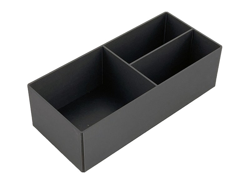 May include: A black plastic storage box with three compartments. The box is empty and has a rectangular shape.