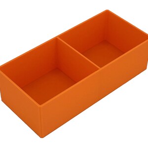 May include: An orange rectangular organiser with two compartments. The organiser is made of a solid material and is designed to hold small items. The compartments are divided by a vertical divider.