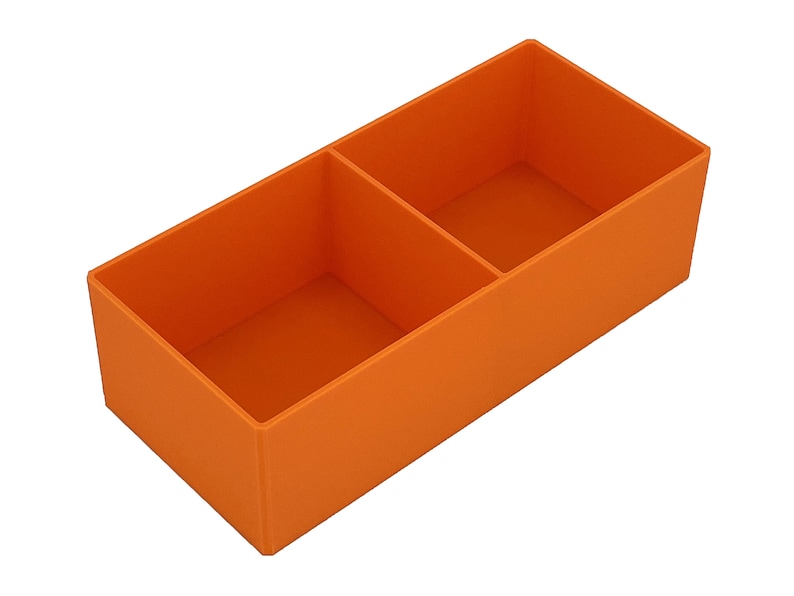 May include: An orange rectangular organiser with two compartments. The organiser is made of a solid material and is designed to hold small items. The compartments are divided by a vertical divider.