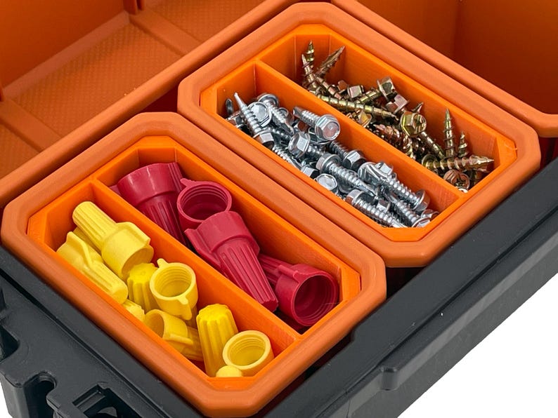 Puede incluir: Una caja de herramientas naranja y negra con tres compartimentos. Los compartimentos est&aacute;n llenos de varios art&iacute;culos de ferreter&iacute;a, incluidos tornillos, tuercas de alambre y conectores el&eacute;ctricos.