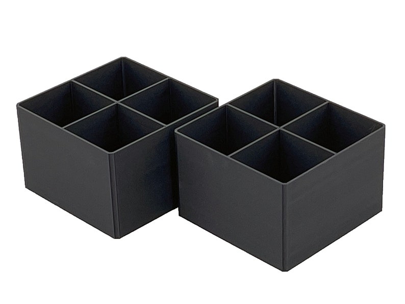 May include: Two black plastic storage boxes with four compartments each. The boxes are empty and have a square shape.