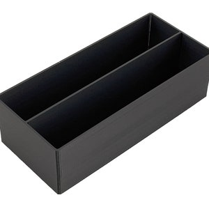 May include: A black plastic storage box with two compartments. The box is rectangular and has a smooth surface.