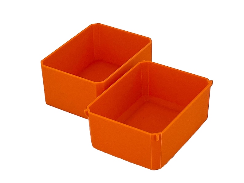 May include: Two bright orange rectangular storage bins are displayed against a white background. The bins are made of a solid material and have a simple, clean design. The bins are empty and ready for use.