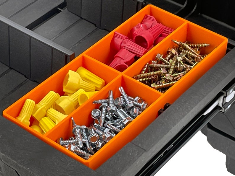 May include: An orange organiser tray with several compartments containing hardware. The tray holds yellow and red wire connectors, alongside various screws, including hex head and wood screws. The tray is inside a black toolbox.