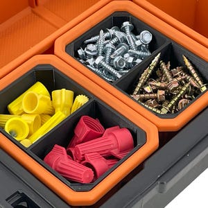 Op de afbeelding: Een zwarte en oranje plastic opbergdoos met vier compartimenten. De compartimenten zijn gevuld met verschillende hardware-artikelen, waaronder schroeven, draadmoeren en elektrische connectoren.
