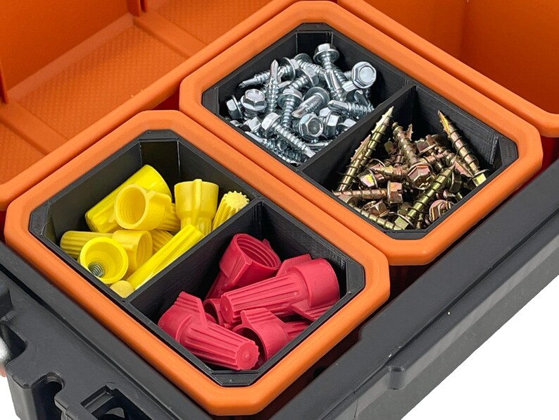 Op de afbeelding: Een zwarte en oranje plastic opbergdoos met vier compartimenten. De compartimenten zijn gevuld met verschillende hardware-artikelen, waaronder schroeven, draadmoeren en elektrische connectoren.