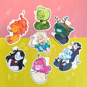 Może przedstawiać: Zestaw dziesięciu kolorowych naklejek z postaciami z kreskówki Adventure Time. Naklejki są wydrukowane na białym, błyszczącym papierze i przedstawiają Finna Człowieka, Jake'a Psa, Księżniczkę Bubblegum, Marceline Królową Wampirów, BMO, Króla Lodowego, Księżniczkę Lumpy Space, Księżniczkę Flame i wiele innych.