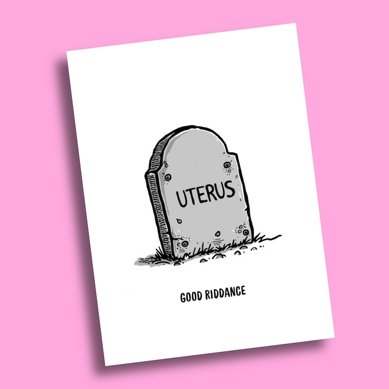 May include: A white greeting card featuring a black and white line drawing of a grey tombstone with the word UTERUS written on it. Below the tombstone, the text GOOD RIDDANCE is printed in black capital letters on the white card surface.