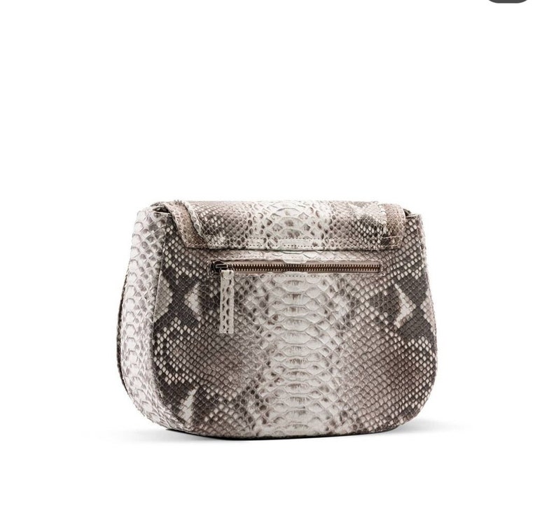 Pode incluir: Uma bolsa de m&atilde;o de couro de cobra com padr&atilde;o branco e marrom com fecho de correr.