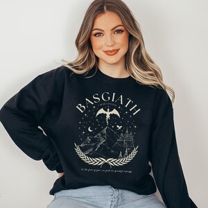 May include: Black sweatshirt with a graphic design featuring the word "BASGIATH" above a mountain scene with a castle, a winged figure, and the text "In the face of fear, we find our greatest courage."