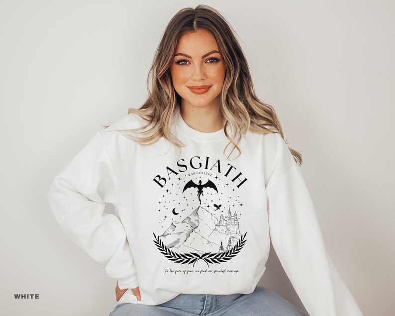 May include: White sweatshirt with a black graphic design featuring the word "BASGIATH" above a mountain scene with a dragon, stars, and a castle. The text "In the face of fear, we find our greatest courage" is below the graphic.