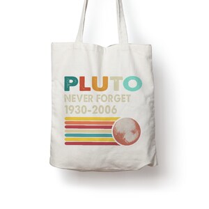 Könnte beinhalten: Beige Tragetasche mit dem Wort "PLUTO" in bunten Buchstaben. Darunter steht der Text "NEVER FORGET 1930-2006". Ein Retro-Design aus bunten Streifen und eine Planetengrafik befindet sich ebenfalls auf der Tasche.