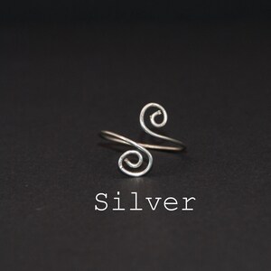 Op de afbeelding: Een zilveren ring met een dubbel spiraal ontwerp. De ring is simpel en elegant.
