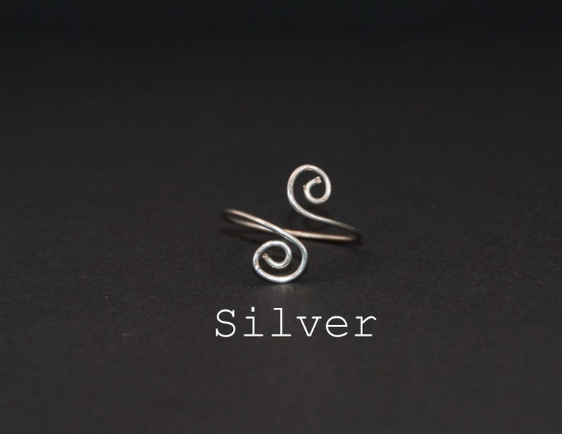 Op de afbeelding: Een zilveren ring met een dubbel spiraal ontwerp. De ring is simpel en elegant.