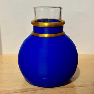 May include: A blue glass vase with a gold rim. The vase is round and has a wide mouth.