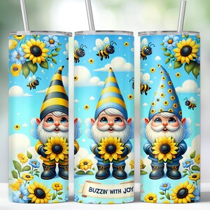 Puede incluir: Tres vasos de acero inoxidable con fondo azul y diseño de gnomo. Cada gnomo lleva un gorro a rayas amarillo y negro y sostiene un girasol. El texto "Buzzin' with Joy" está impreso en la parte inferior del vaso.