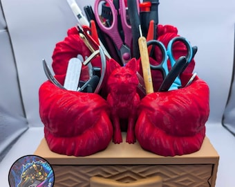 May include: Red 3D printed fox-shaped desk organizer with a drawer. The organizer has two compartments for holding pens, pencils, and other small items. The fox is standing on a brown base with a drawer.