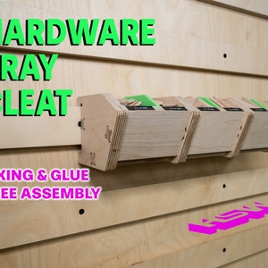 May include: A wooden hardware tray cleat with the text "FIXING & GLUE FREE ASSEMBLY" on the front. The cleat is mounted on a light wood wall and has four trays attached to it.