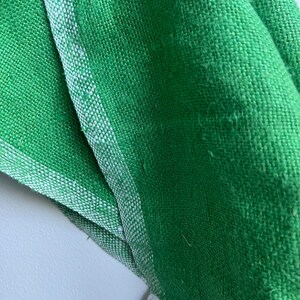 Pu&ograve; includere: Primo piano di un tessuto verde con un bordo bianco. Il tessuto ha una trama tessuta ed &egrave; piegato.