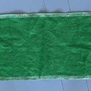 Pu&ograve; includere: Un tappeto rettangolare verde con un bordo bianco. Il tappeto &egrave; fatto di un materiale morbido e testurizzato.