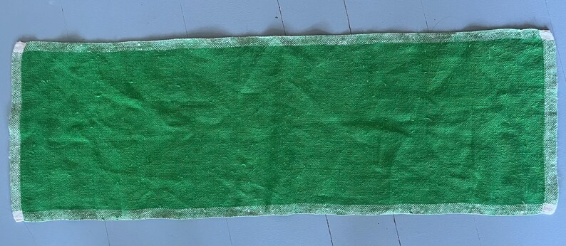Pu&ograve; includere: Un tappeto rettangolare verde con un bordo bianco. Il tappeto &egrave; fatto di un materiale morbido e testurizzato.