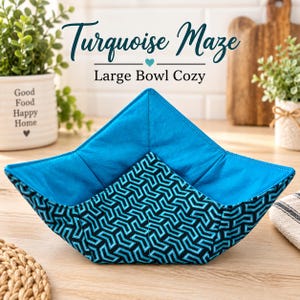May include: A large bowl cozy featuring a black and turquoise geometric maze pattern on the exterior and a solid turquoise interior. The fabric is quilted with visible stitching, forming a square shape with four pointed corners for holding bowls.