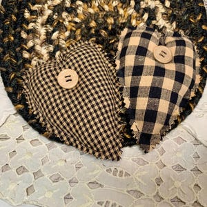 May include: Two black and tan gingham heart-shaped pillows with frayed edges and a button in the center of each.