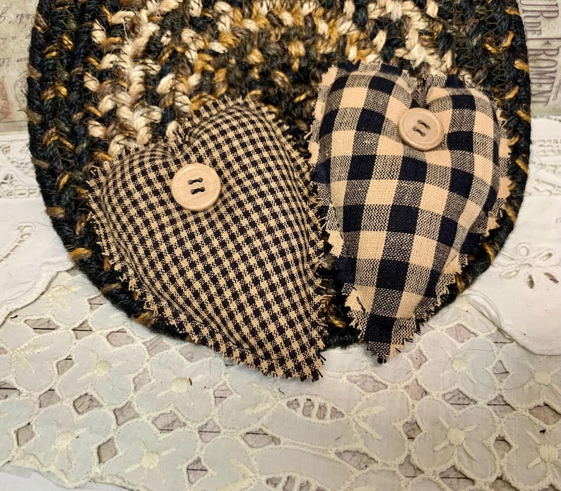May include: Two black and tan gingham heart-shaped pillows with frayed edges and a button in the center of each.