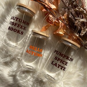 May include: Three glass jars with bamboo lids and clear straws. The jars have orange and brown text that reads "Autumn Coffee Books", "Hello Autumn", and "Pumpkin Spice Latte".