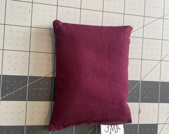 May include: A burgundy fabric bean bag with a white label that says "JMA" on it.