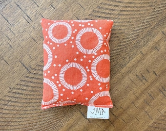 May include: A small orange fabric pouch with a white circle pattern. The pouch has a white label with the text "JMA" on it.